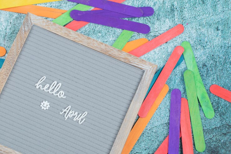 Foto gratuito hola frase de abril en el tablero gris con pegatinas de colores alrededor