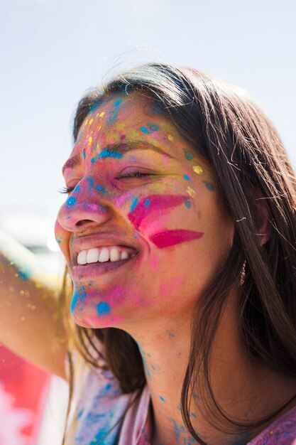 Holi de color sobre el rostro de la mujer sonriente.