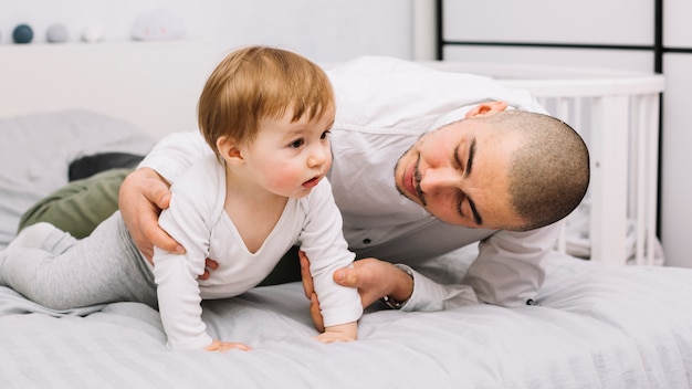 Hombre abrazando al pequeño bebé acostado en la cama