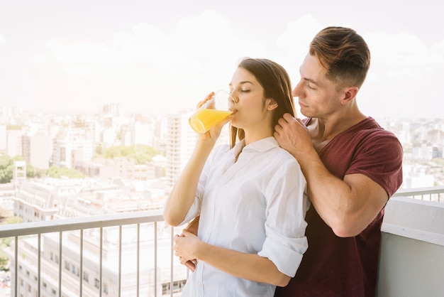 Hombre abrazando a mujer con jugo de vidrio