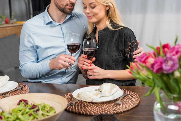 Hombre abrazando a la mujer en la mesa con flores y plato de ensalada