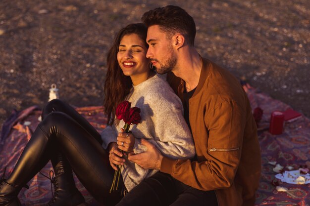 Hombre abrazando a mujer con rosas rojas en coverlet