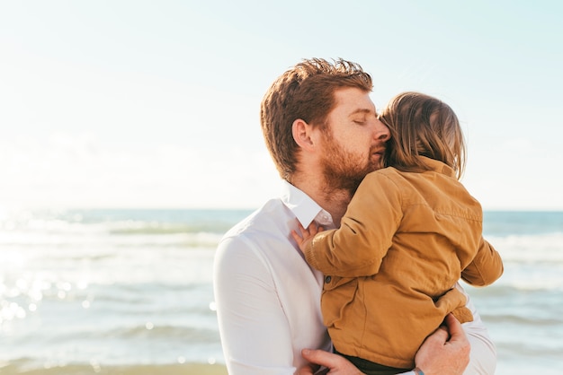 Foto gratuita hombre abrazando a un niño a la orilla del mar