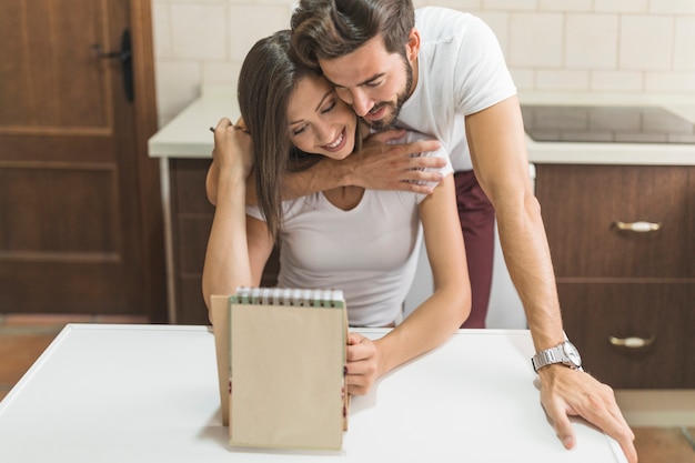 Hombre abrazando a novia con bloc de notas