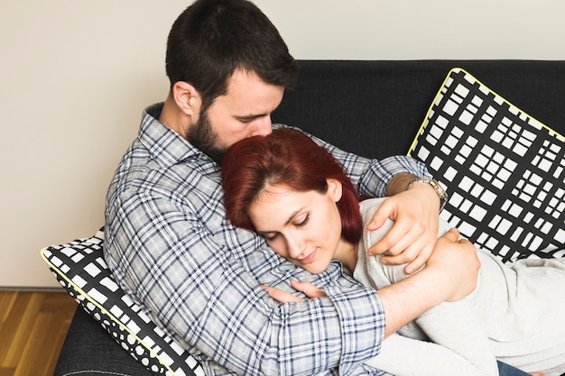 Foto gratuita hombre abrazando a su esposa en el sofá