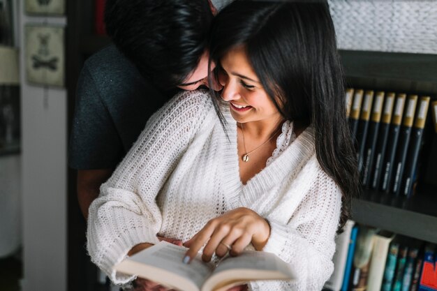 Hombre abrazando a su novia desde atrás sosteniendo el libro