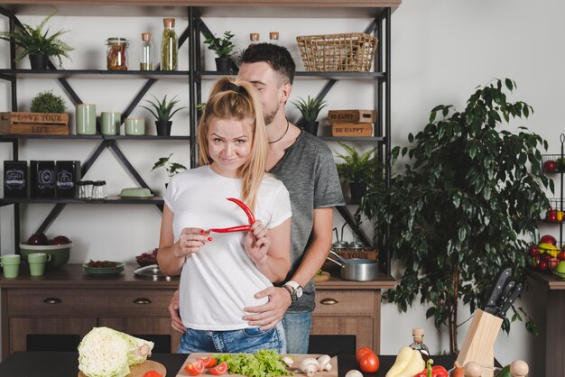 Hombre abrazando a su novia con chile rojo en la mano