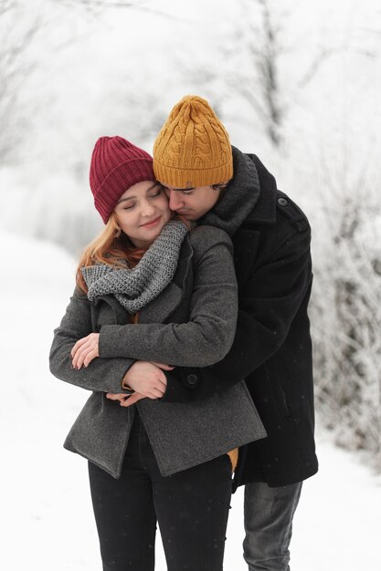Hombre abrazando a su novia en un parque congelado