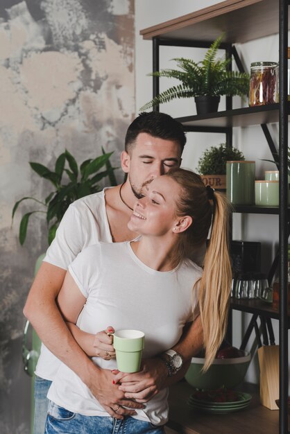 Hombre abrazando a su novia sosteniendo una taza de café