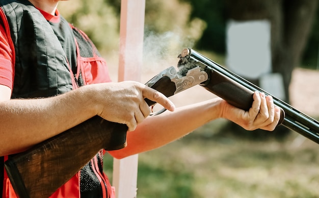 El hombre abre el perno de escopeta después de un disparo con humo