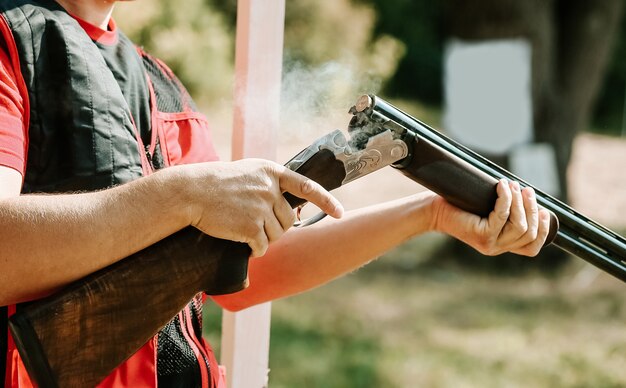 El hombre abre el perno de escopeta después de un disparo con humo