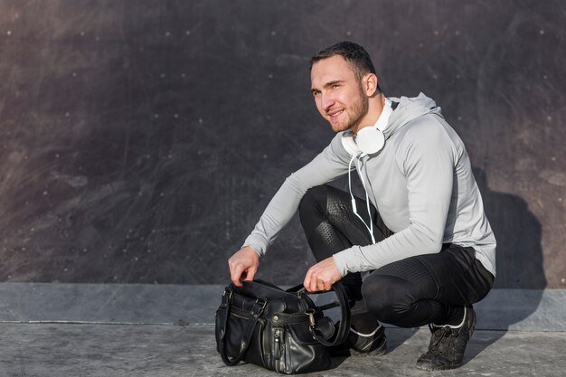 Hombre abriendo una bolsa de deporte y mirando a otro lado