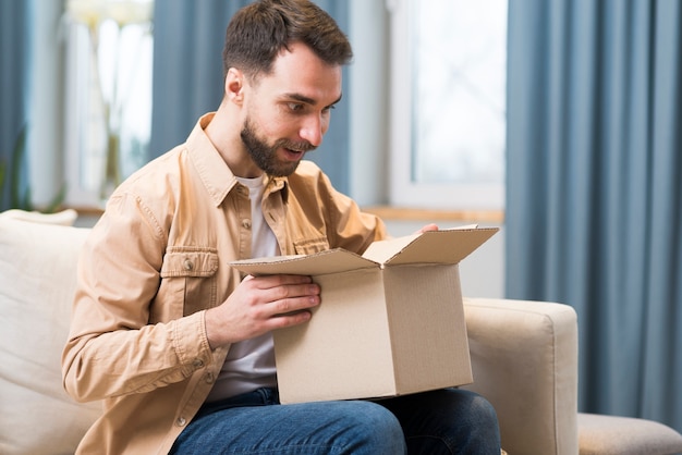 Hombre abriendo la caja de bien que ordenó en línea