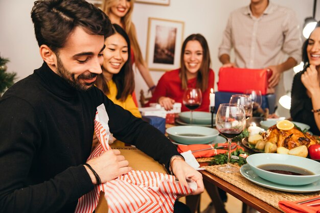 Hombre abriendo caja de regalo en cena de navidad