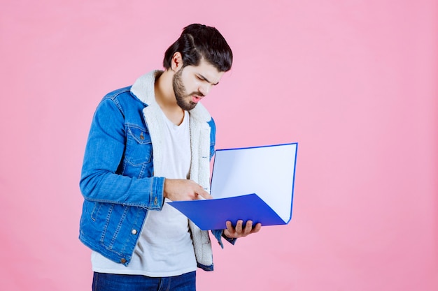 Foto gratuita hombre abriendo una carpeta azul y comprobándola