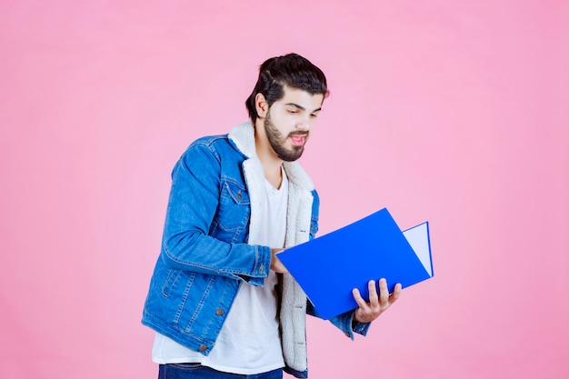 Hombre abriendo una carpeta azul y comprobándola