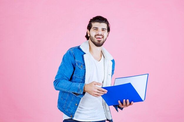 Hombre abriendo una carpeta azul y comprobándola