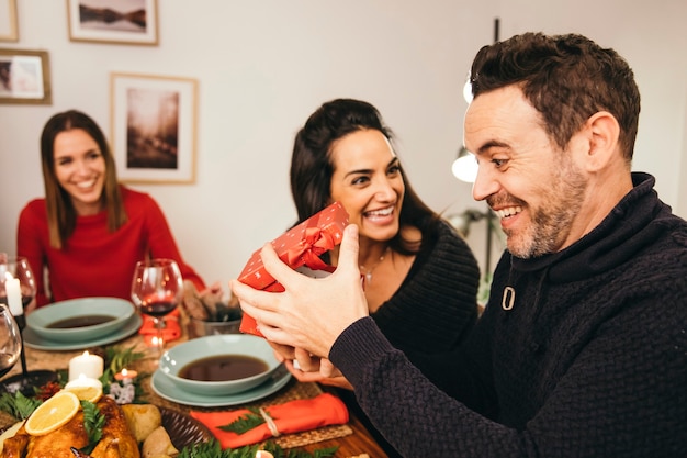 Hombre abriendo regalo en cena de navidad