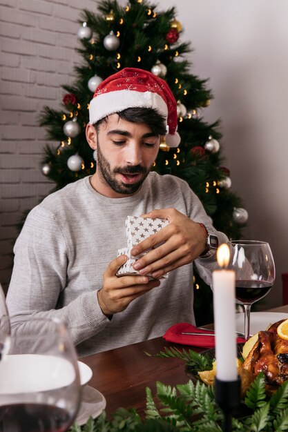 Hombre abriendo regalo en cena de navidad