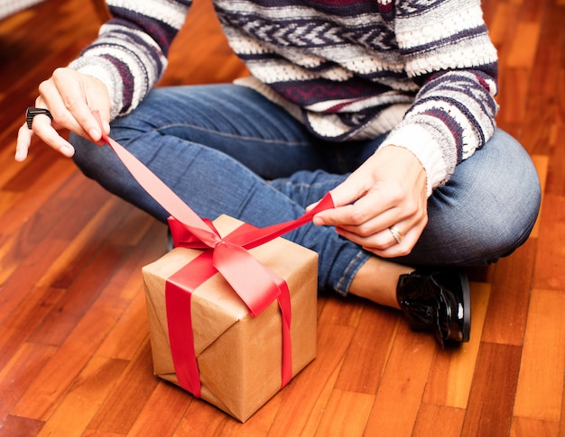 Foto gratuita hombre abriendo un regalo sentado en el suelo