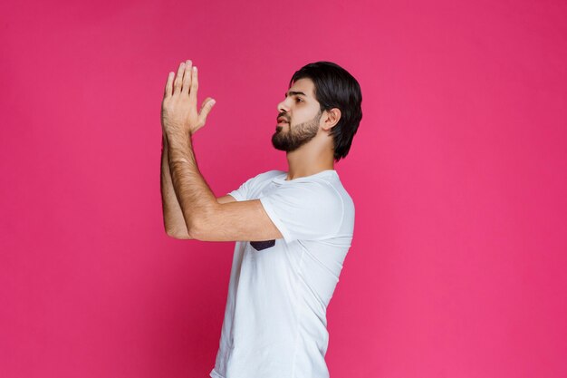 Hombre abriendo y uniendo sus manos para rezar por algo.