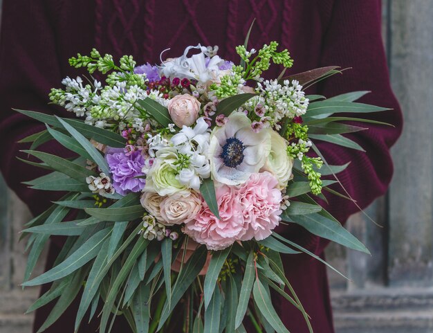 Hombre con abrigo burdeos con un ramo de flores mixtas