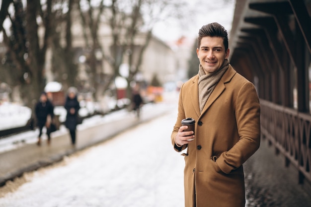 Hombre en abrigo con café afuera