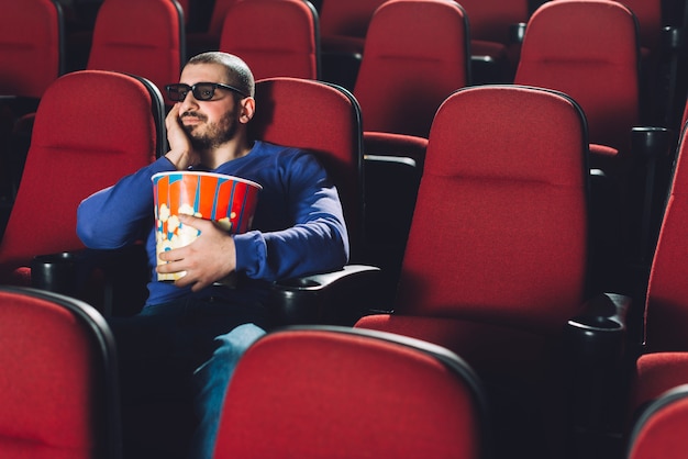 Hombre aburrido viendo la película en el cine