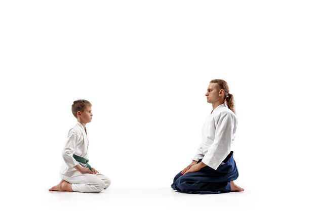 Hombre y adolescente en el entrenamiento de aikido en la escuela de artes marciales. concepto de deporte y estilo de vida saludable. luchadores en kimono blanco karate hombres en uniforme se saludan.