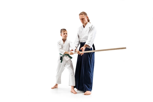 Hombre y adolescente luchando con espada de madera en el entrenamiento de Aikido en la escuela de artes marciales