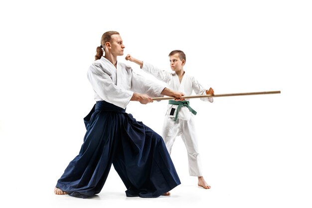 Hombre y adolescente peleando con espada de madera en el entrenamiento de Aikido en la escuela de artes marciales.