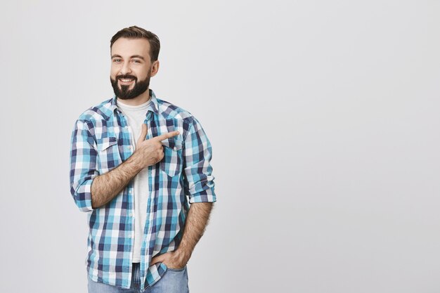 Hombre adulto con barba apuntando con el dedo a la derecha, copyspace