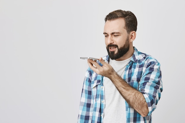 Hombre adulto con barba grabar mensaje a través del altavoz del teléfono