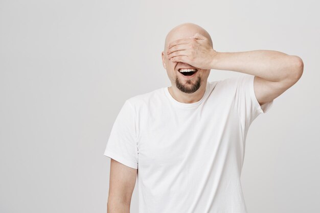 Hombre adulto Calvo emocionado con barba cerrar los ojos con la palma, sonriendo