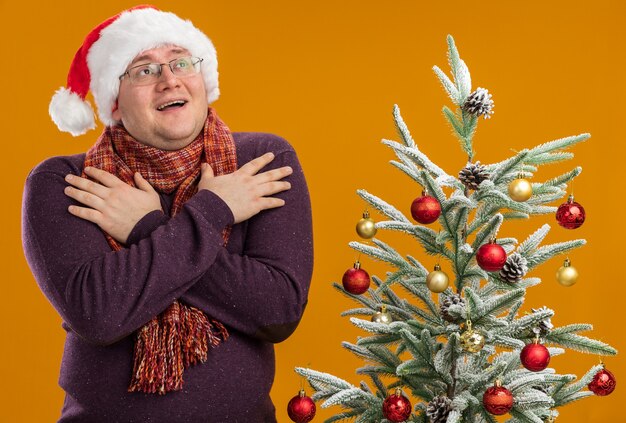 Hombre adulto emocionado con gafas y gorro de Papá Noel con bufanda alrededor del cuello