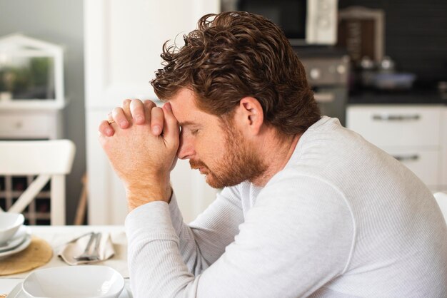 Hombre adulto emocional orando en casa
