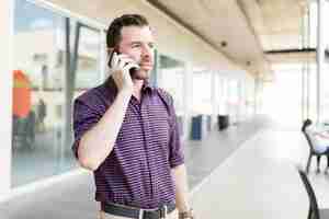 Foto gratuita hombre adulto medio tomando una llamada en el teléfono inteligente mientras está de pie en el centro comercial