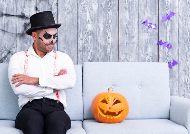 Hombre adulto mirando calabaza de halloween