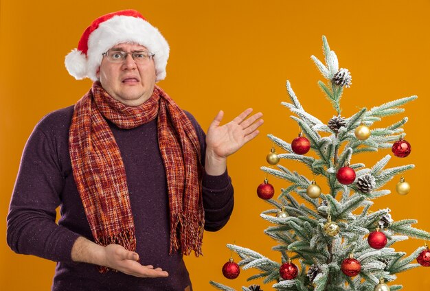 Hombre adulto molesto con gafas y gorro de Papá Noel con bufanda alrededor del cuello