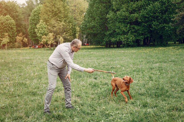 Hombre adulto en un parque de verano con un perro