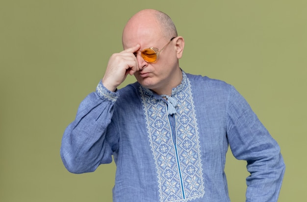 Hombre adulto pensativo en camisa azul con gafas de sol poniendo la mano en la frente