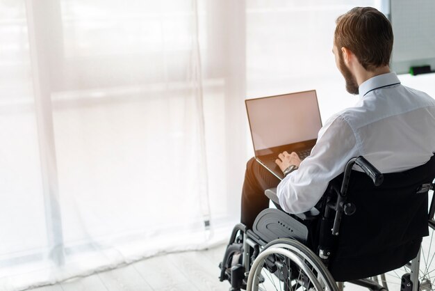 Hombre adulto en silla de ruedas trabajando en una computadora portátil