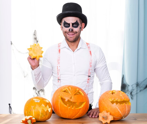 Hombre adulto sonriente con calabazas de halloween