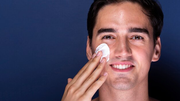 Hombre adulto sonriente con el uso de productos para el cuidado de la piel