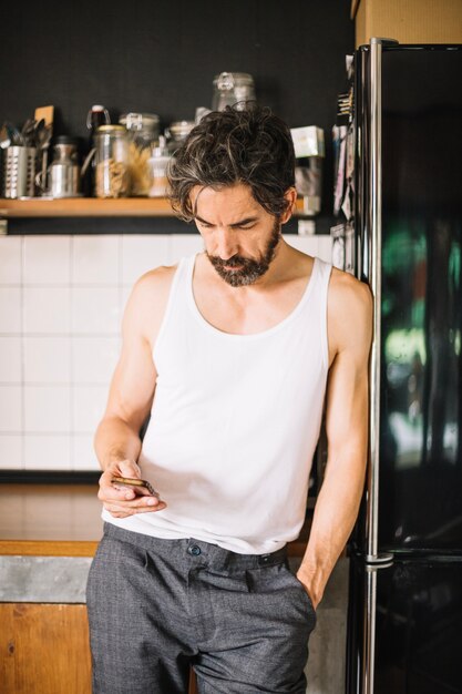 Hombre adulto con teléfono en la cocina