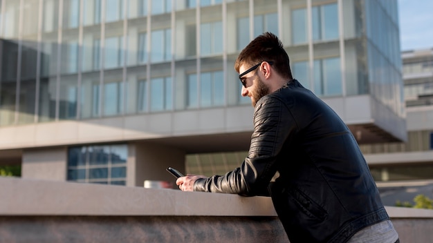 Hombre adulto usando teléfono móvil afuera durante la puesta de sol