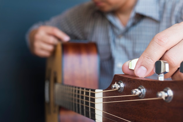 Foto gratuita hombre afinando guitarra acústica