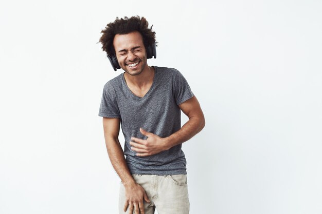 Hombre africano alegre en auriculares riendo Ojos cerrados.