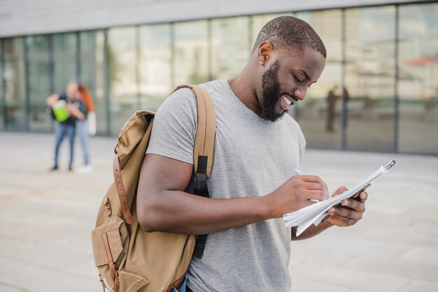 Hombre africano alegre escribiendo en papeles