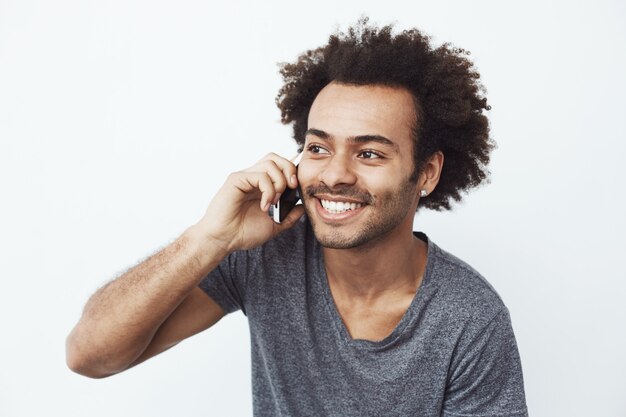 Hombre africano alegre sonriendo hablando por teléfono.